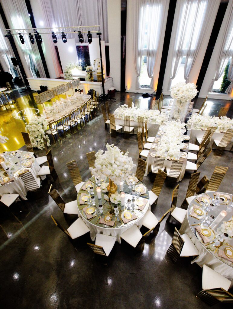 Aerial view of a luxury wedding reception layout with mixed table shapes, tall floral arrangements, and gold design elements created by Events D’Lux.