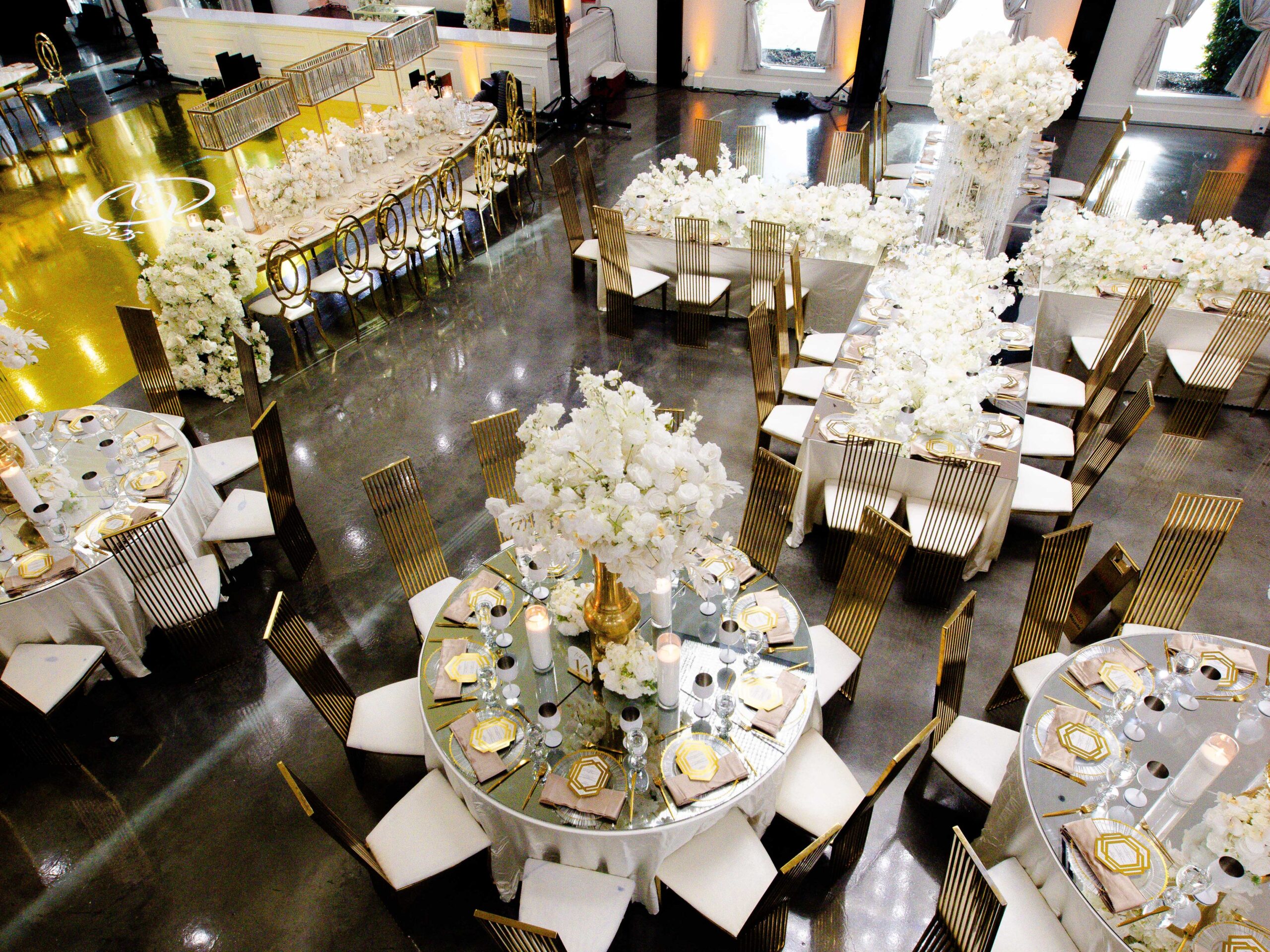 Luxury wedding layout featuring mixed round and rectangular tables with mirrored tops and sculptural white florals.