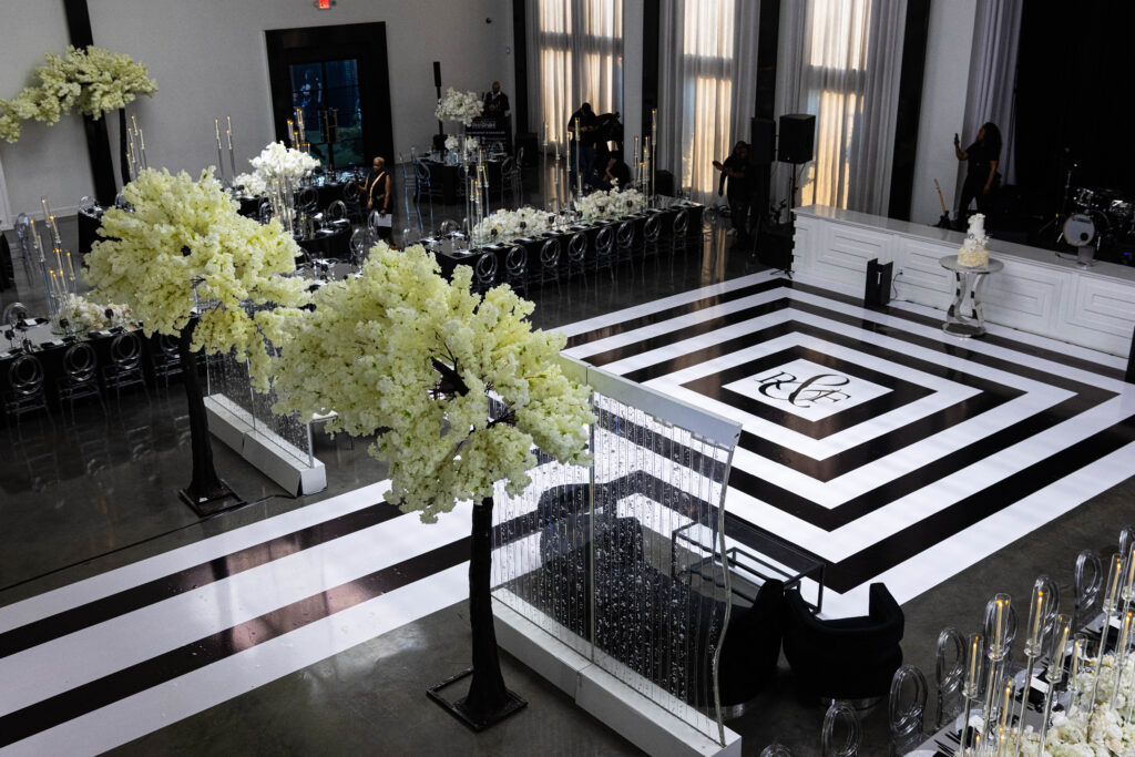 Large sculptural cherry blossom floral installations surrounding a black and white geometric dance floor at a luxury event