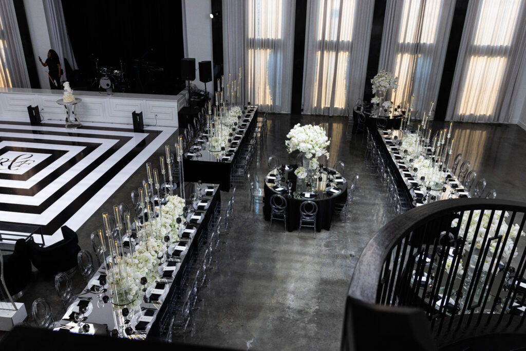 specialty table layout with black-and-white geometric dance floor and tall floral installations.
