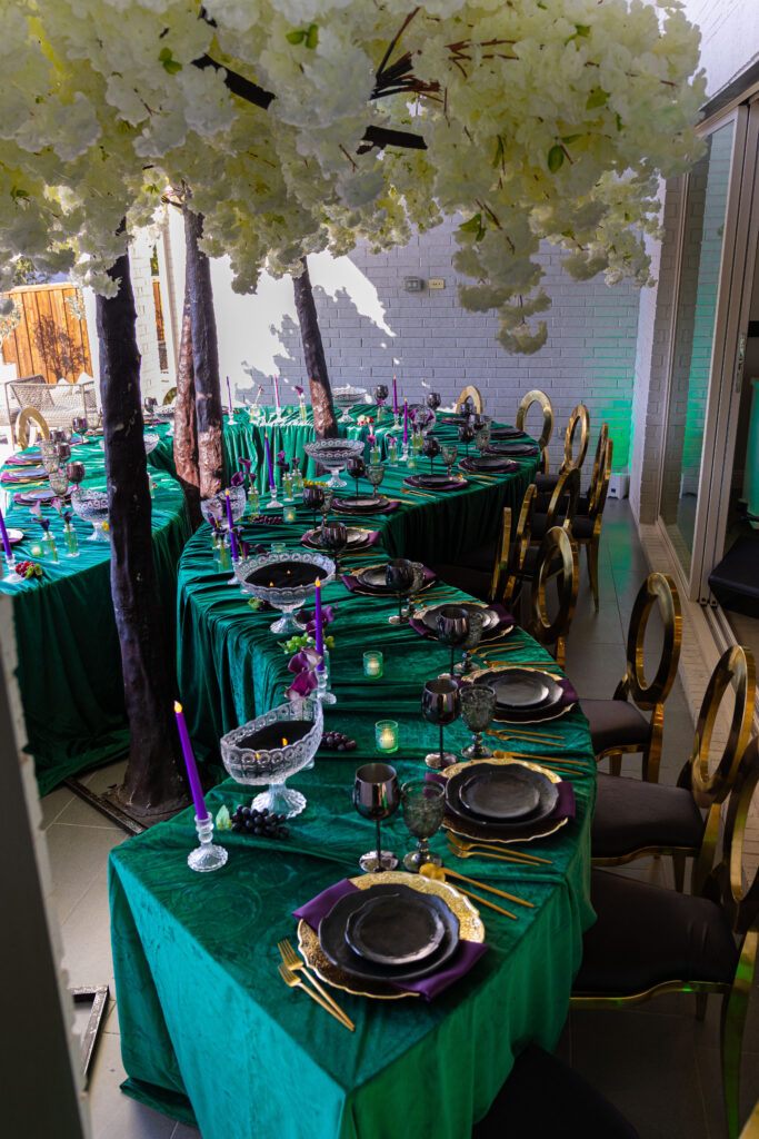 Emerald green luxury tablescape with gold chairs and black chargers by Events D’Lux