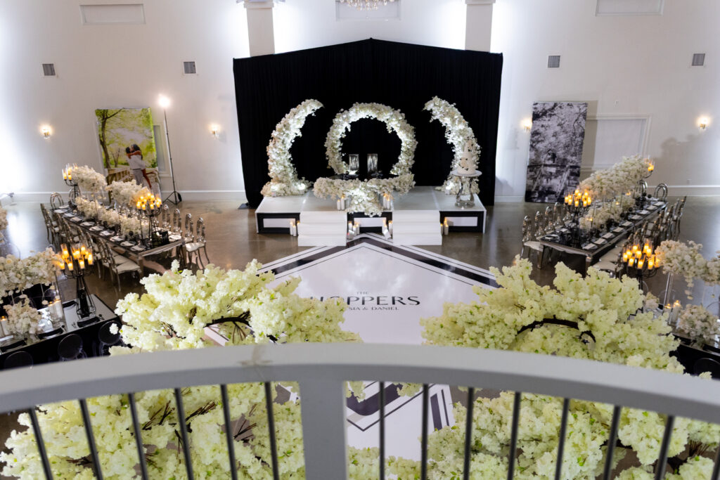 Angled table layout with specialty rental shapes and large floral structures at a luxury wedding event