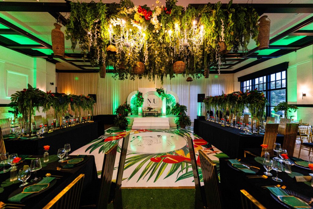 Immersive lighting installation with hanging greenery, chandeliers, and dramatic green uplighting at a luxury event.