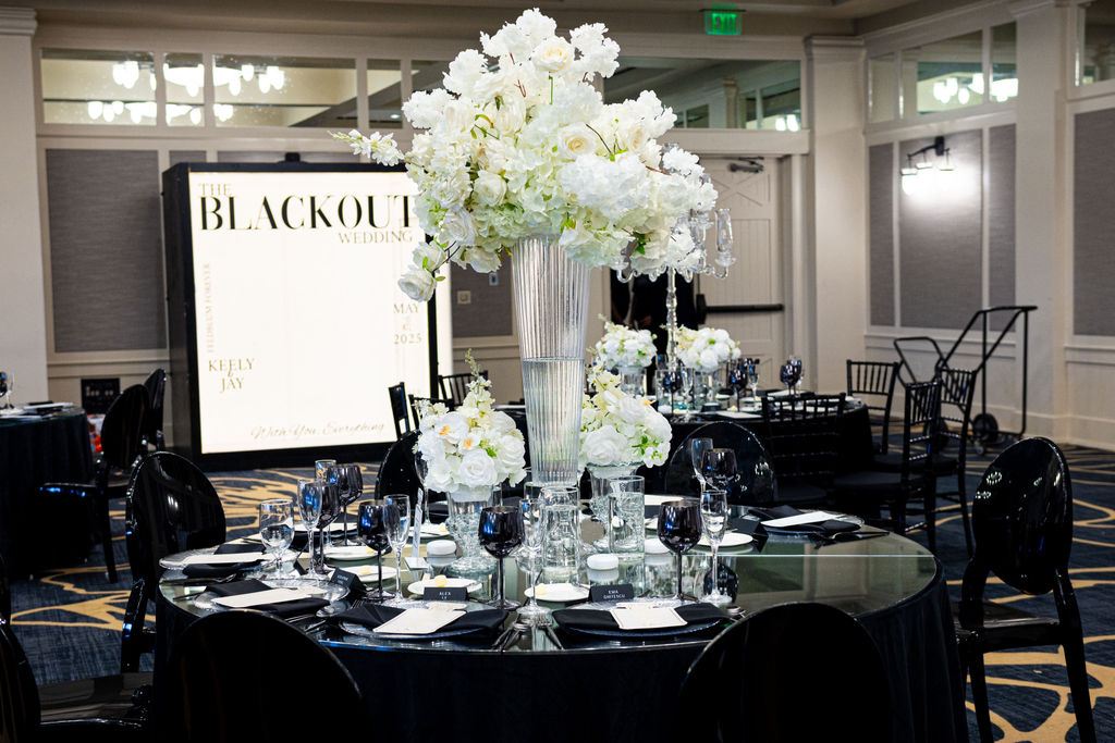 Tall white floral centerpiece with black chairs and editorial-style tablescape designed for photogenic impact.”